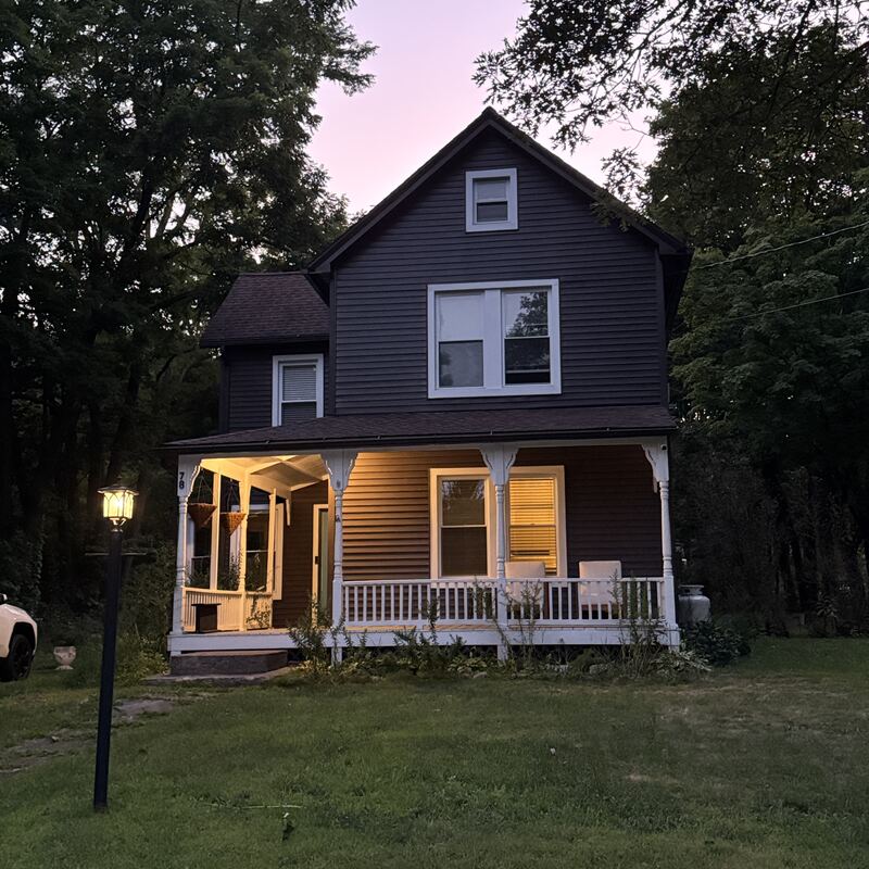 The repainted house glowing at dusk, porch lights on
